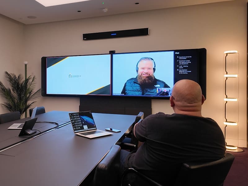 man sitting at a table in front of a large screen