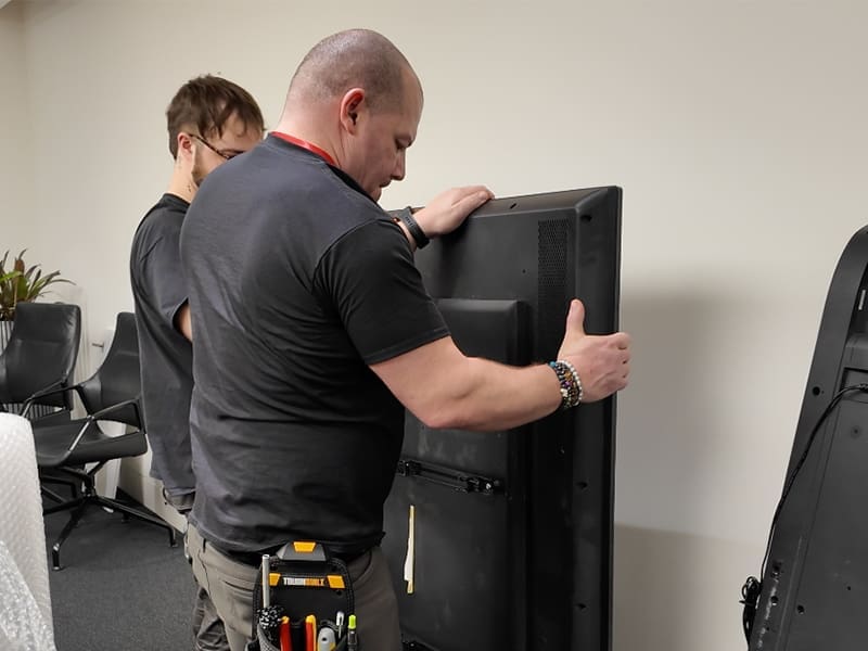 man standing next to a black refrigerator in a room