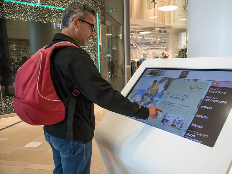 man with a red backpack is looking at a computer screen