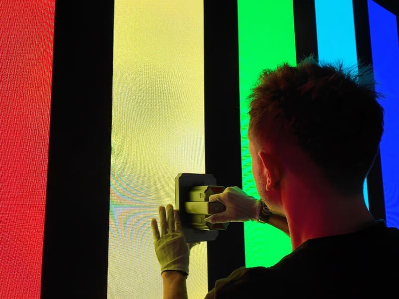 man in a black shirt is painting a rainbow wall