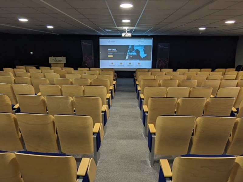 large auditorium with rows of chairs and a projector screen