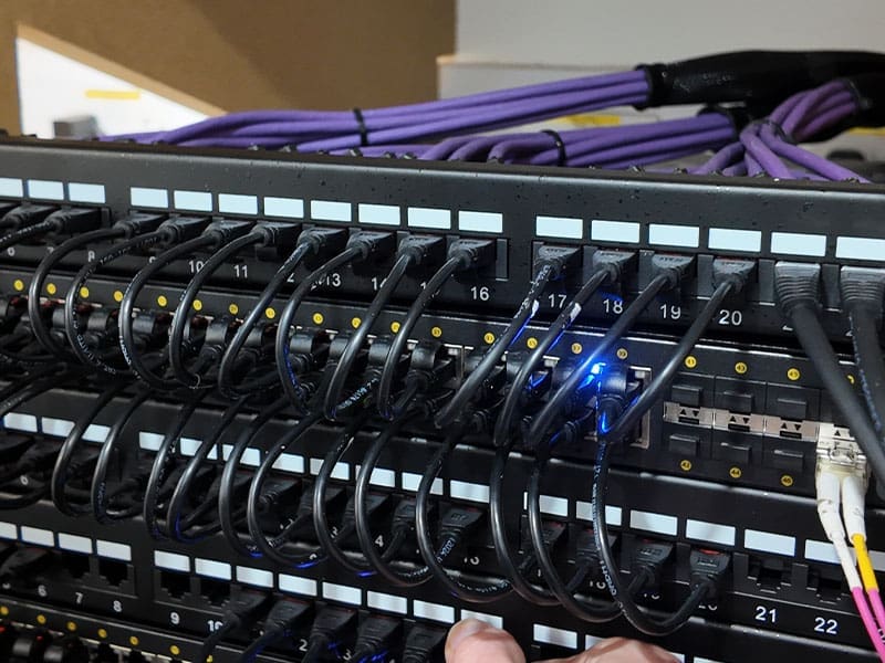 person is holding wires in front of a rack of servers
