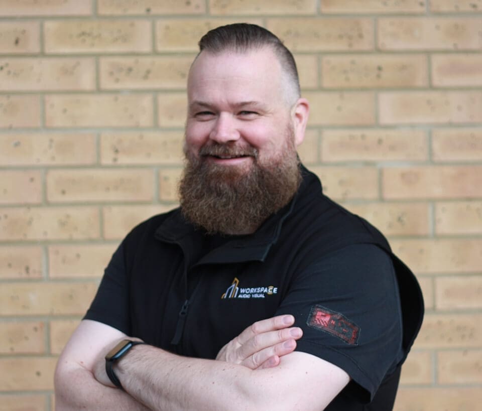 man with a beard standing in front of a brick wall